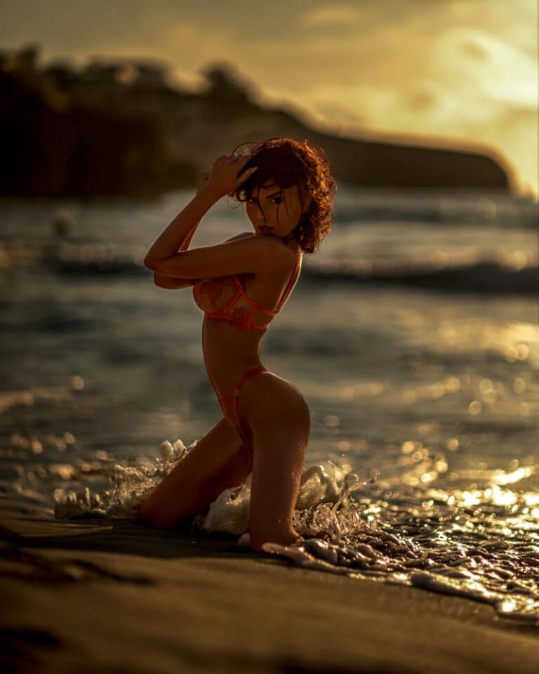 Beach shoot at sunset at Playa de Muro, Mallorca – red-haired model in a bikini kneeling at the waterline