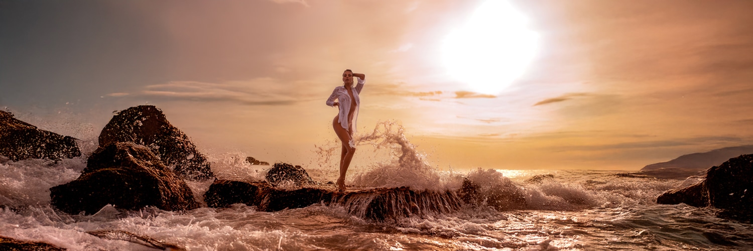 Sunset photoshoot on the coast of Mallorca – model standing on the rocks by the sea