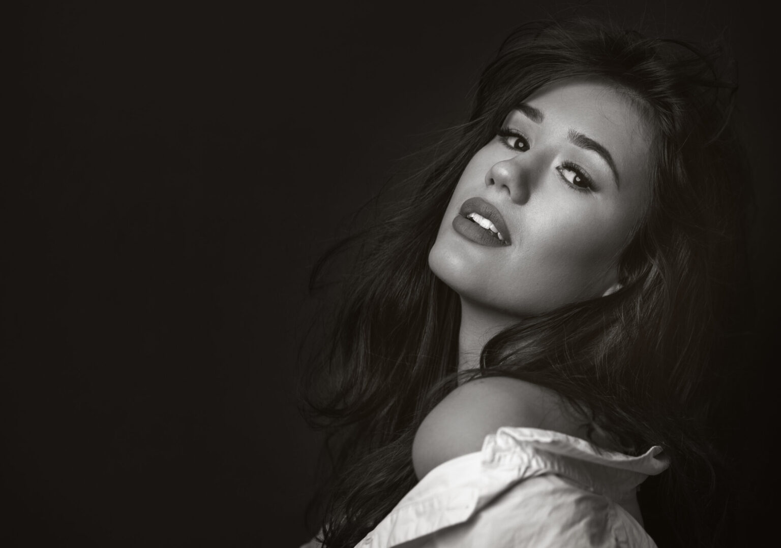 Warm black-and-white business portrait by Marcus Boéll – dark-haired woman with a friendly smile